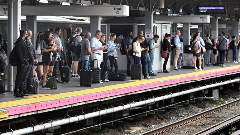 Late afternoon commuters stand on the Jamaica Station platform as a...