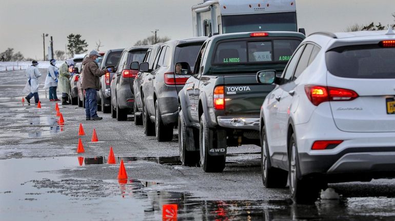 Cars line up at a drive-through COVID-19 testing site for Suffolk...