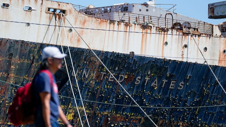 A person walks past the S.S. United States moored on...