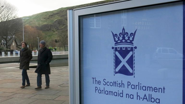 People walk past the Scottish Parliament in Edinburgh, on March...