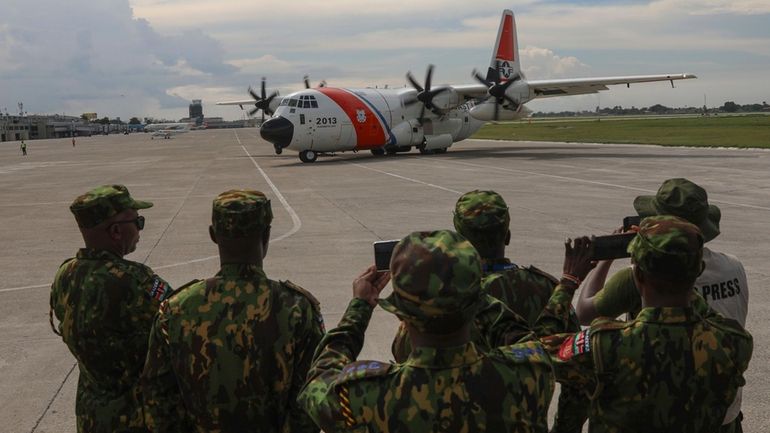 Kenyan police watch as a plane carrying police from Jamaica...