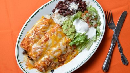 Beef enchiladas served with rice and beans, guacamole,