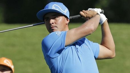 A fan watches Ricky Fowler, right, as he