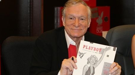 Hugh Hefner smiles while signing copies of the