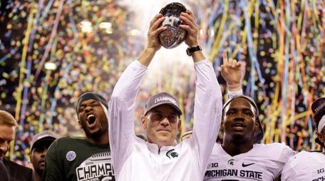 Michigan State coach Mark Dantonio holds the trophy