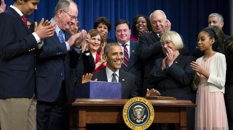 President Barack Obama, center, smiles after signing the
