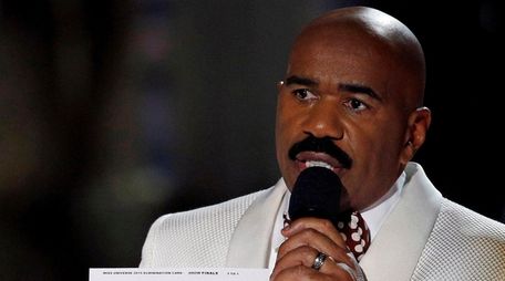 Miss Universe pageant host Steve Harvey holds up