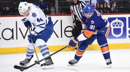 Islanders center John Tavares, right, skates against Maple