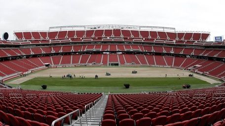 Workers install sod on the field at