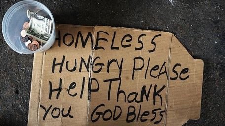 A homeless man's sign rests on the