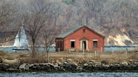 A sailboat passes behind an abandoned building on