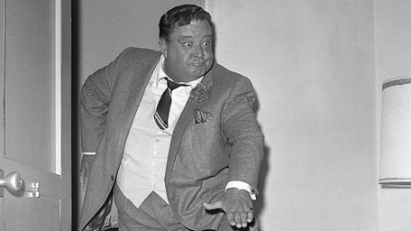 Comedian Jackie Gleason clowns for photographers after