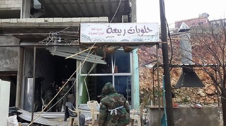 Pro-government forces inspect a building in Rabia in