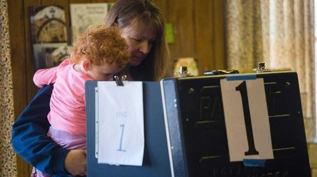 A woman holding her child votes at the