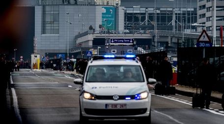 A Belgian police vehicle drives past passengers evacuating