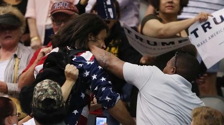 Trump protester Bryan Sanders, center left, is punched