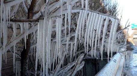 Icicles form on tree branches and a guardrail
