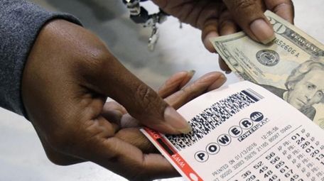 A clerk hands over a Powerball ticket for