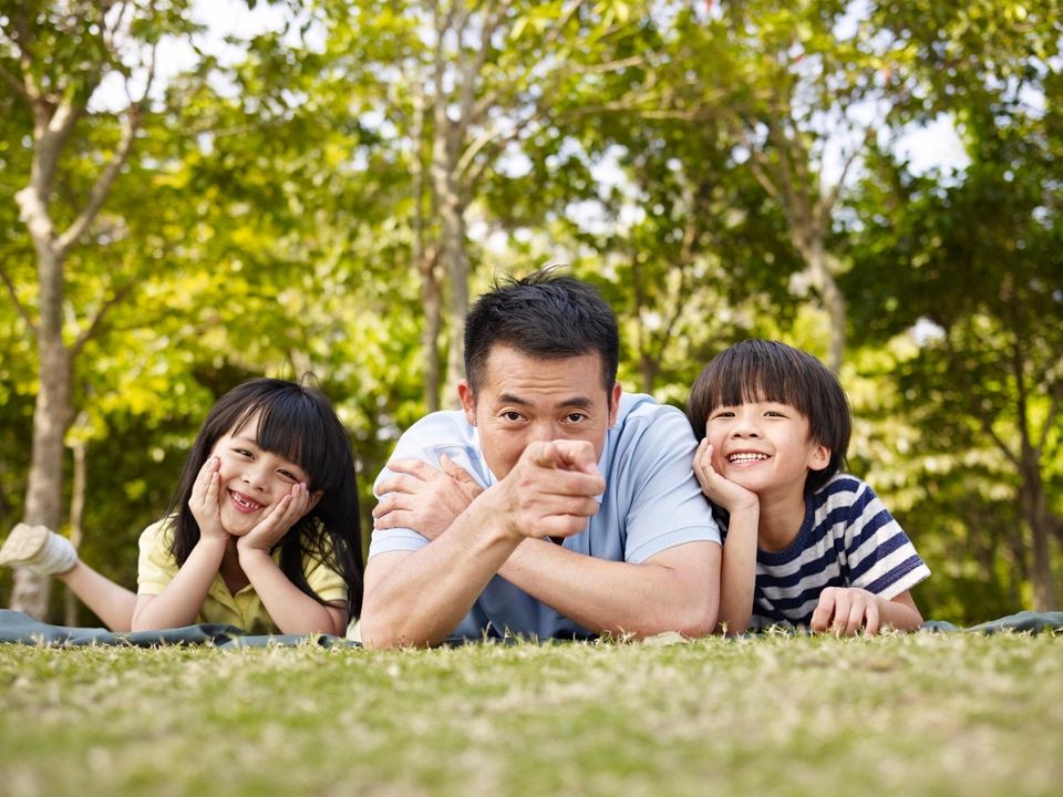 Asian father and children playing on grass in