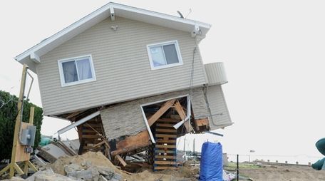 A waterfront house in Babylon hangs precariously Wednesday,