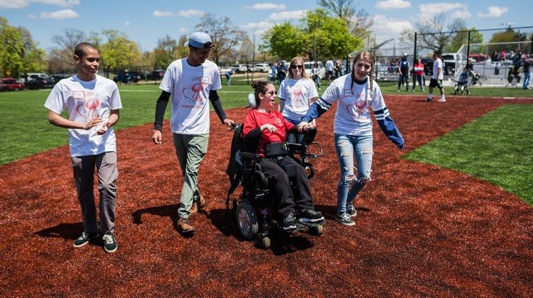 Claire Becker, 13, center, is helped around the