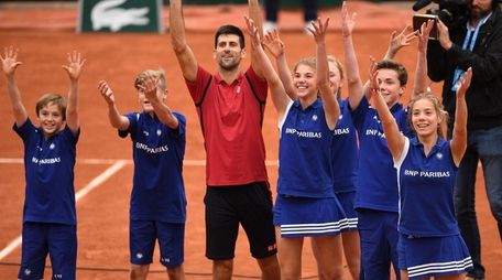 Novak Djokovic celebrates victory with the ballkids during