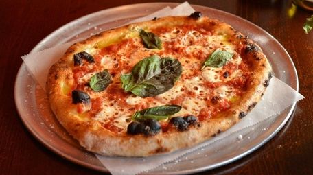 A margherita pizza wears a whisper of mozzarella,
