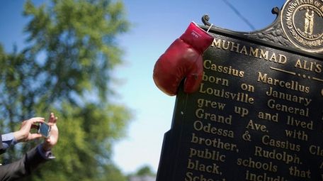 Boxing gloves hang on a historical marker outside