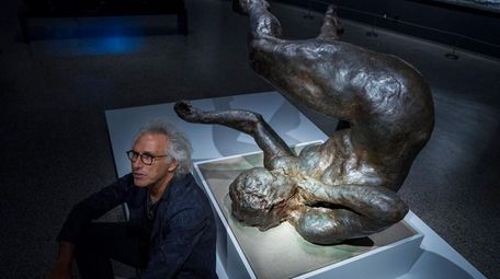 Artist Eric Fischl sits next to his sculpture