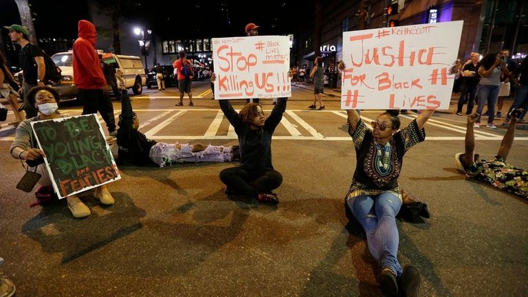 Demonstrators sit on a street during a protest