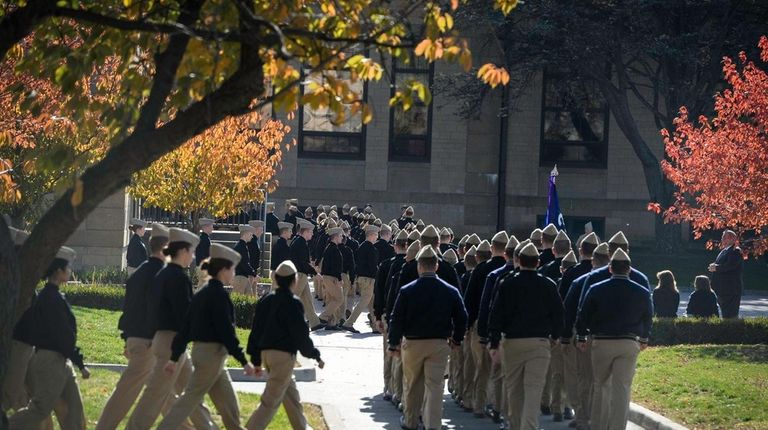 Midshipmen walk in file on the campus of