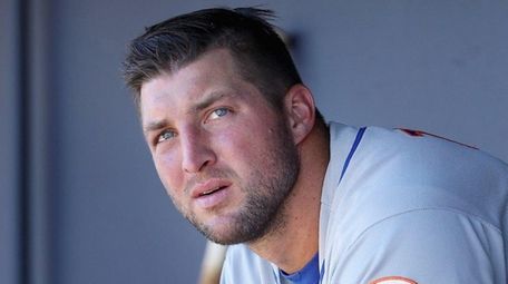 Tim Tebow watches from the dugout during an