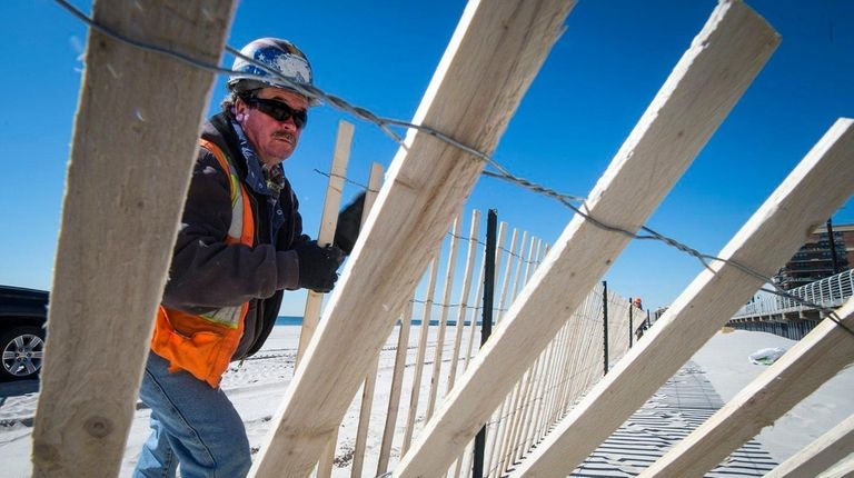 A construction worker puts in fencing where beach