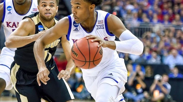 Kansas guard Devonte' Graham, right, drives to the