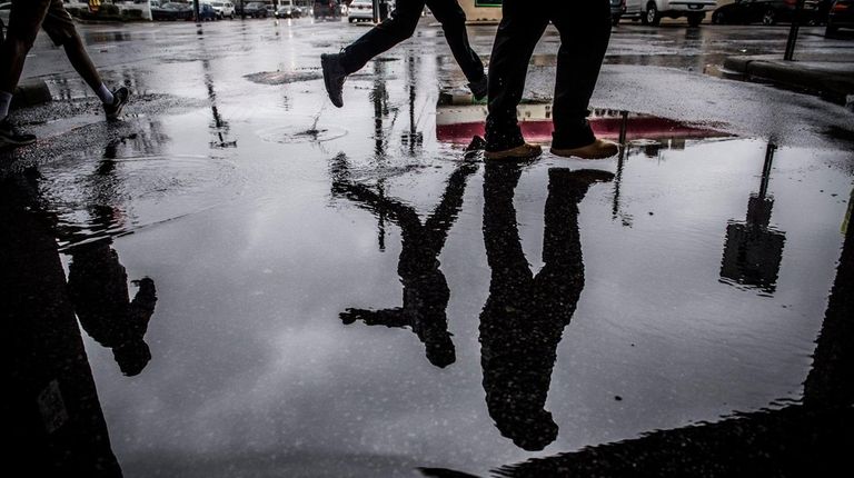 Pedestrians make their way through puddled streets in
