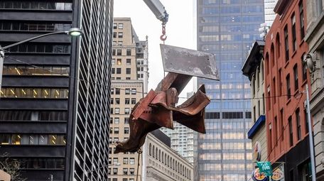 Iron workers remove a steel beam, recovered from
