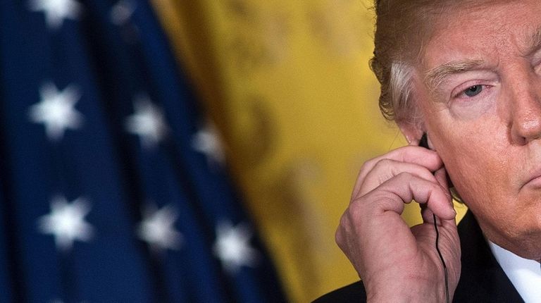President Donald Trump listens to a translation of