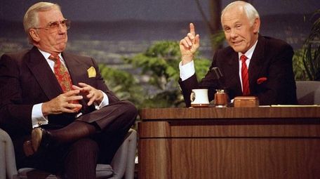 Johnny Carson, behind the desk, with show announcer