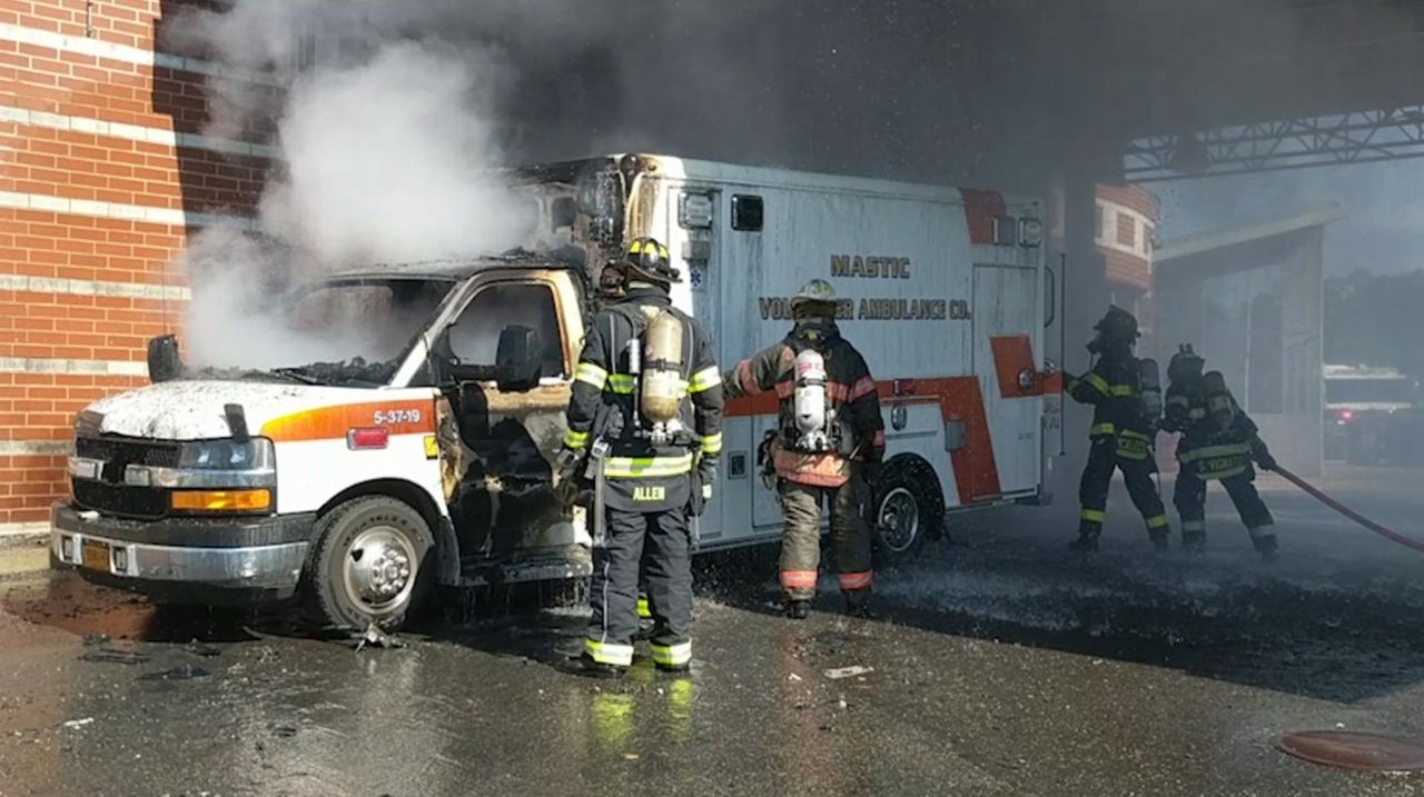 Firefighters from several departments extinguish an ambulance fire