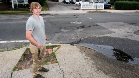 Nick Gluth stands in front of potholes outside