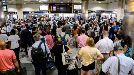 Passengers watch the LIRR departures board in Penn
