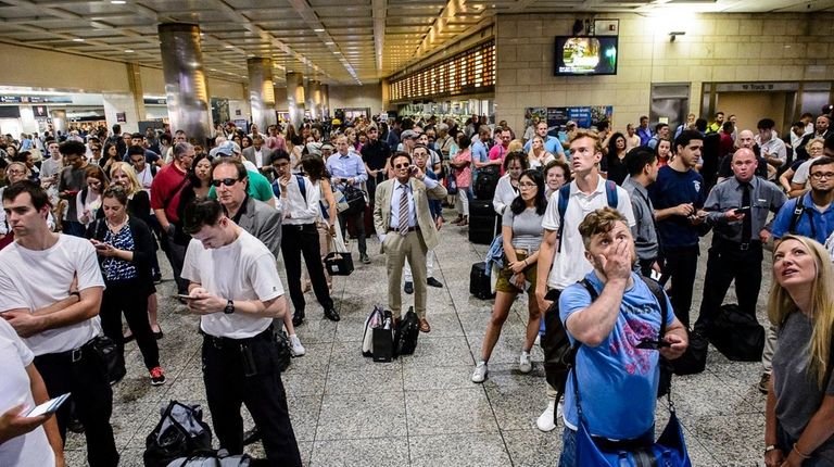 Passengers watch the LIRR departures board in Penn