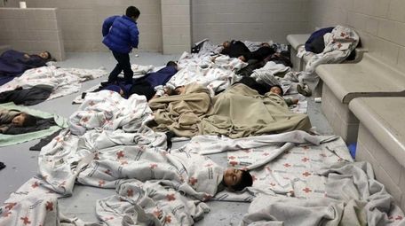 Detainees sleep in a holding cell at a