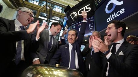 Altice founder Patrick Drahi, center, is applauded as
