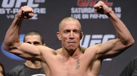 Georges St-Pierre flexes during the weigh-in for UFC