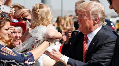 President Donald Trump tries to hold a baby