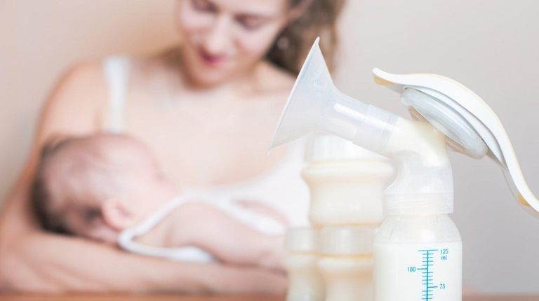 Manual breast pump and mother feeding at background,