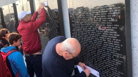 A woman reflects on the wall of names