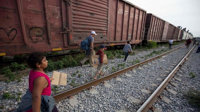 Migrants walk along railroad tracks after getting off