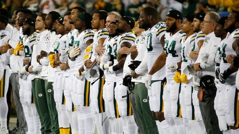 Green Bay Packers link arms during the national